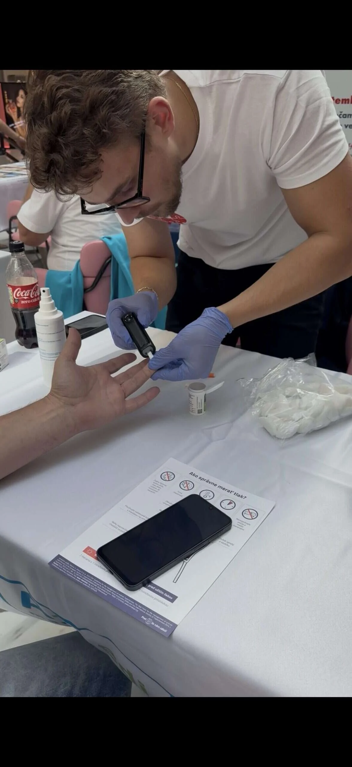 Zdravotník odoberá kvapku krvi z prsta počas preventívneho merania pre verejnosť